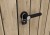 Zbliżenie na czarną klamkę zamkniętą na kłódkę w schowku narzędziowym Deco Ashwood.